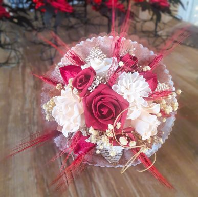 Bouquet de fleurs en rouge et crème, décoré de perles et de feuillage.