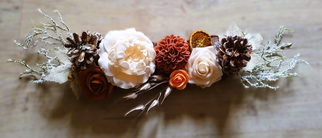 Arrangement de fleurs séchées, pommes de pin et éléments naturels dans des tons chauds.