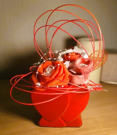 Composition florale avec roses rouges et embellissements en fil métallique.