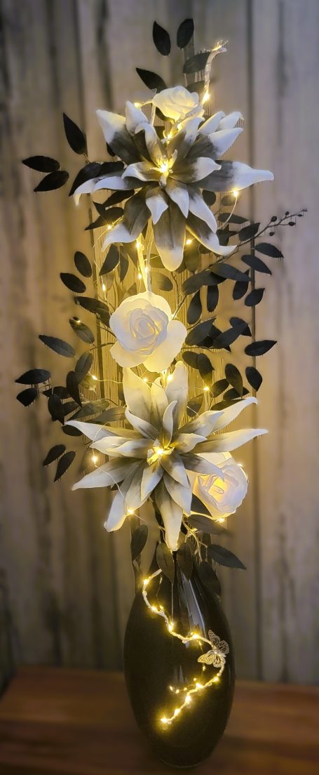 Vase décoratif avec des fleurs blanches et des lumières LED scintillantes.
