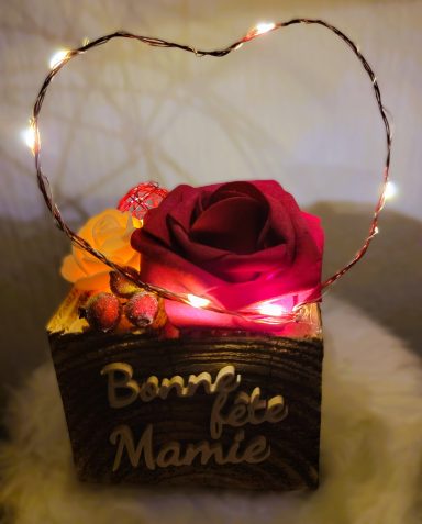 Coffret décoré avec une rose rouge, des fleurs et un cœur lumineux.