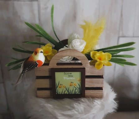 Panier décoratif avec fleurs jaunes, feuille verte et oiseau coloré.