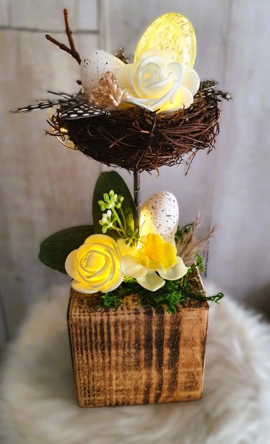 Décor floral avec œufs, roses blanches et lumière douce dans un pot en bois.