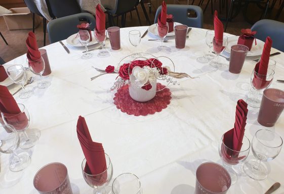 Table dressée avec des serviettes rouges et un centre de table floral.