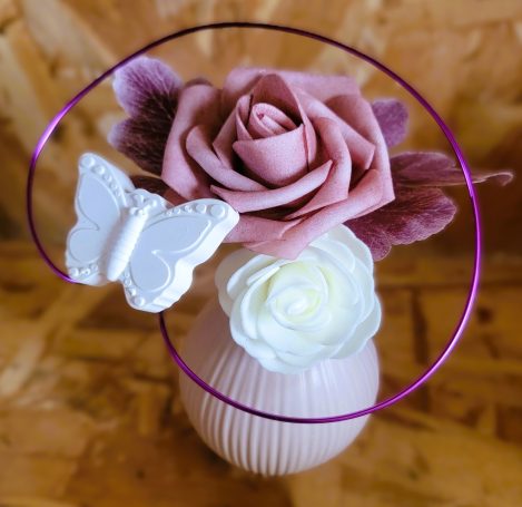 Vase avec des roses et une décoration en forme de papillon.