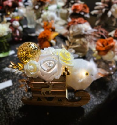 Décor de Noël avec une luge en bois, des fleurs et un oiseau délicat.