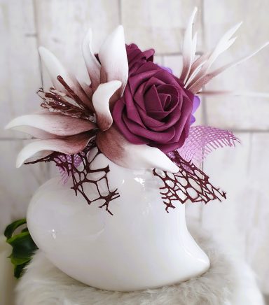Vase blanc avec des fleurs violettes et blanches, décoré de dentelle.