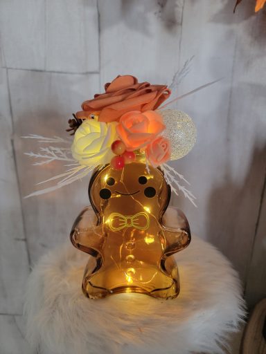Un bonhomme en pain d'épice lumineux ornée de fleurs en pâte et de lumières.