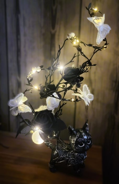 Vase en forme de hibou avec des fleurs blanches et des lumières scintillantes.