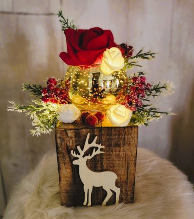 Bouquet de fleurs avec roses rouges et blanches, décoré de lumières et figurine de renne.