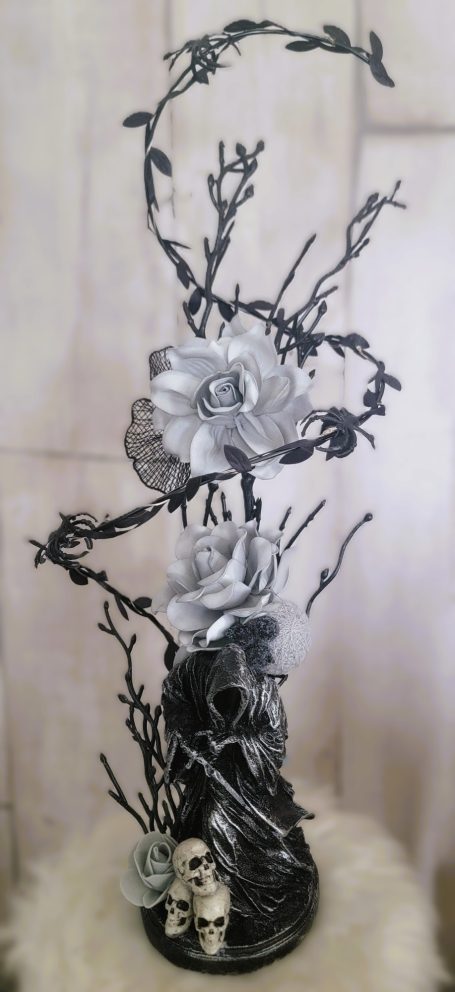 Sculpture stylisée avec fleurs, branches, crâne et décorations gothiques.