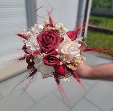 Bouquet rond de roses rouges et fleurs blanches avec des accents dorés et des embellissements.