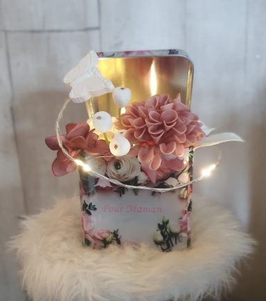 Vase décoratif avec des fleurs roses et une guirlande lumineuse sur un fond clair.